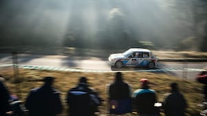 Rally car driving along a road in front of a crowd of spectators