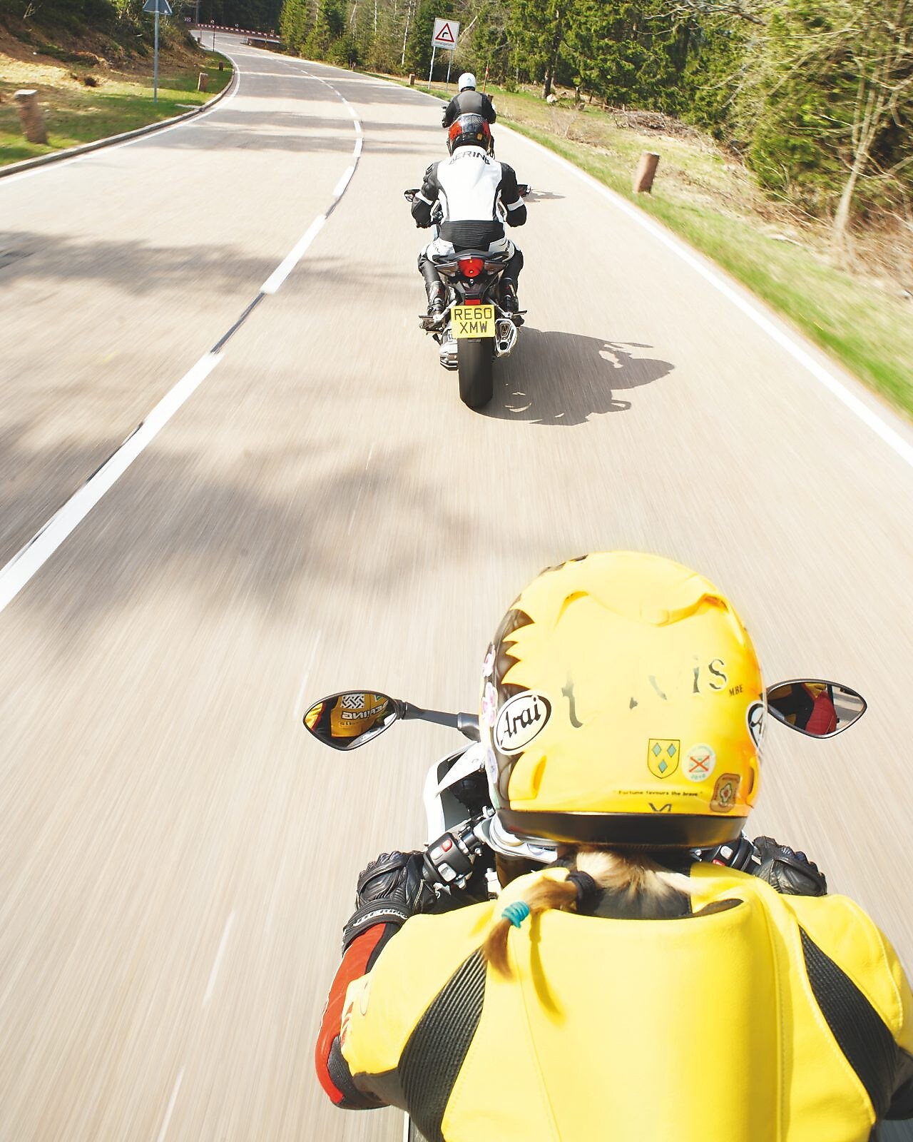 Three motorbikes being ridden along a mountain road