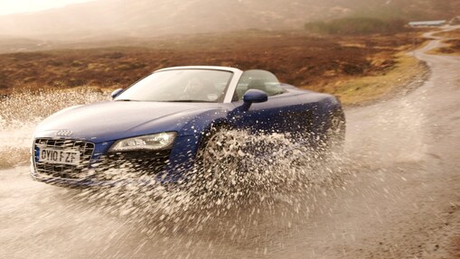 Man driving a car through a large puddle of water