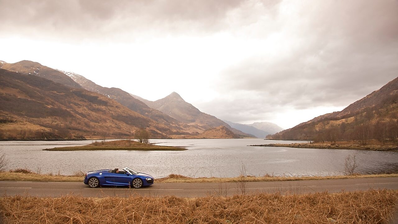 Car on the road by a mountain lake