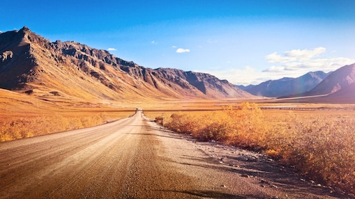 Empty dirt road surrounded by mountains