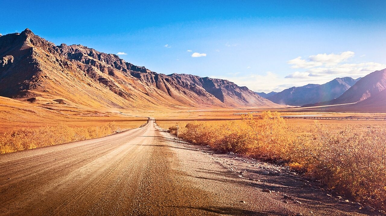 Empty dirt road surrounded by mountains