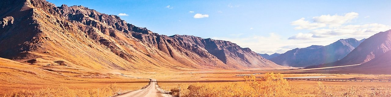 Empty dirt road surrounded by mountains