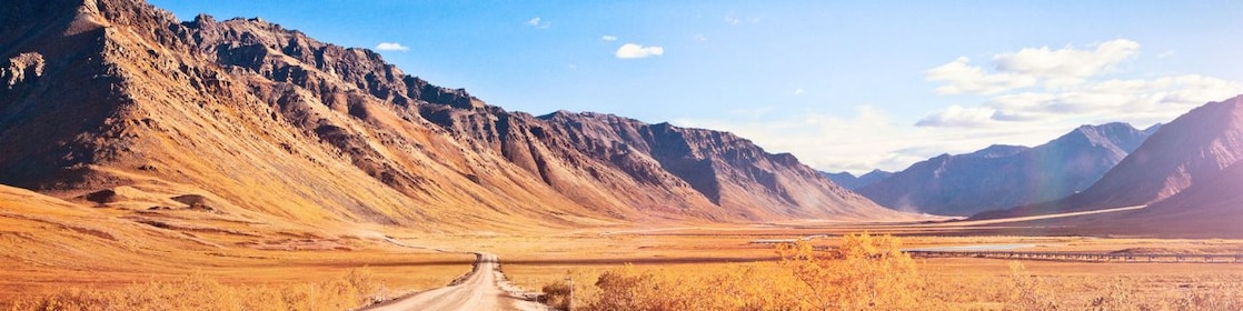Empty dirt road surrounded by mountains