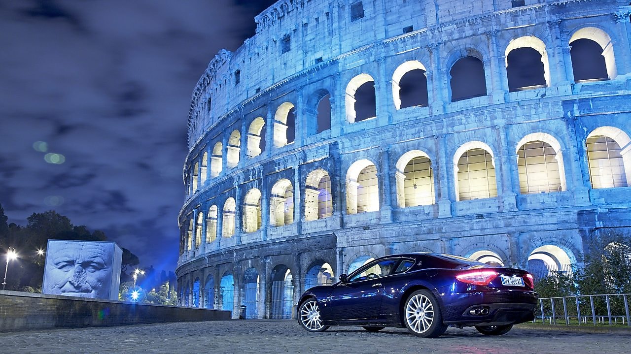 Car parked outside of the Colosseum in Rome at night
