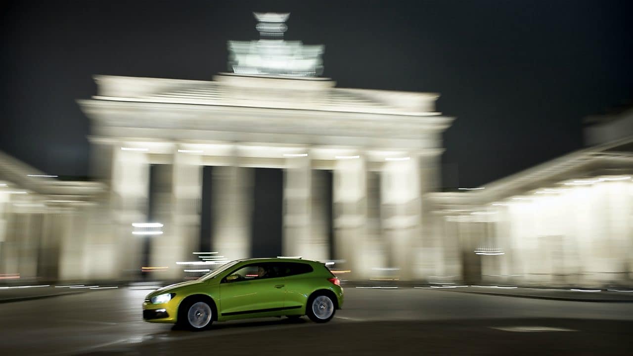 green car driving fast at night