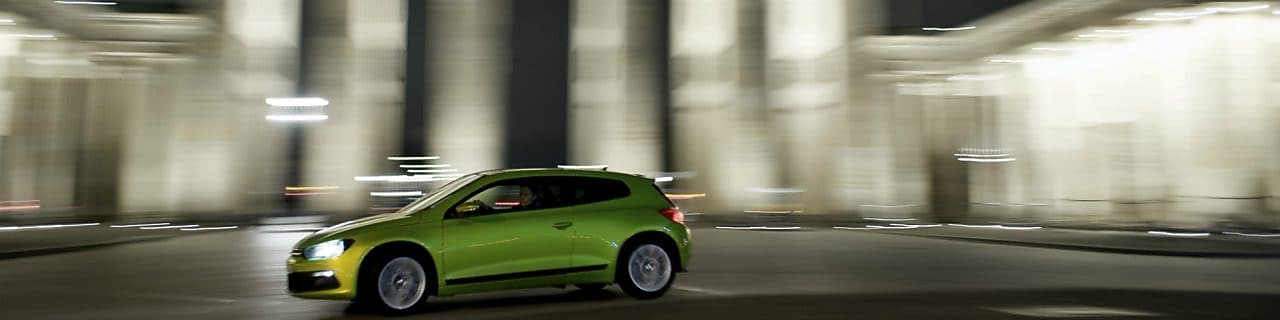 green car driving fast at night