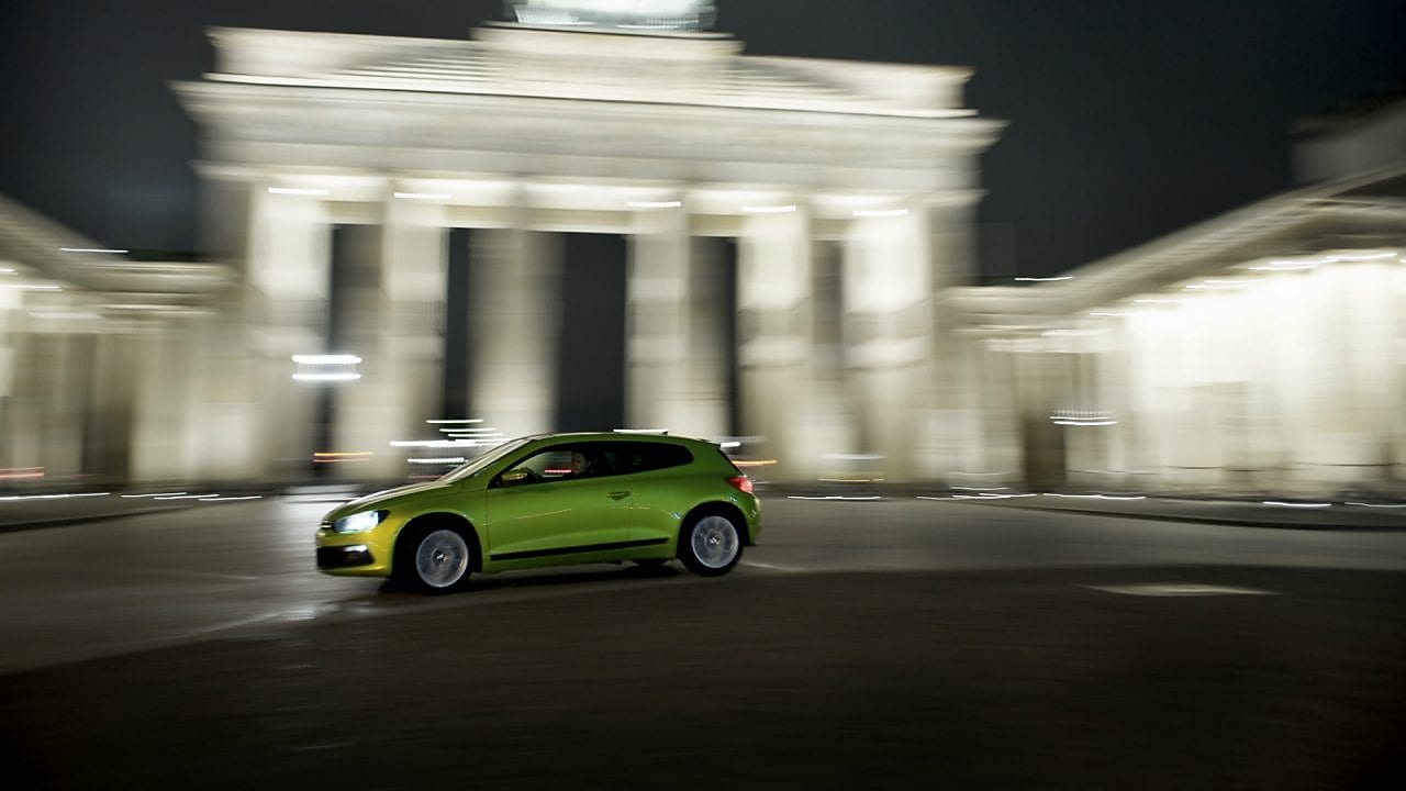 green car driving fast at night