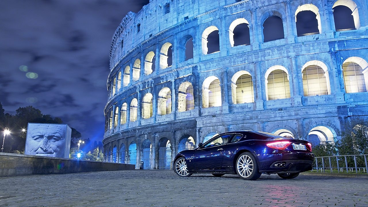 Car parked outside of the Colosseum in Rome at night
