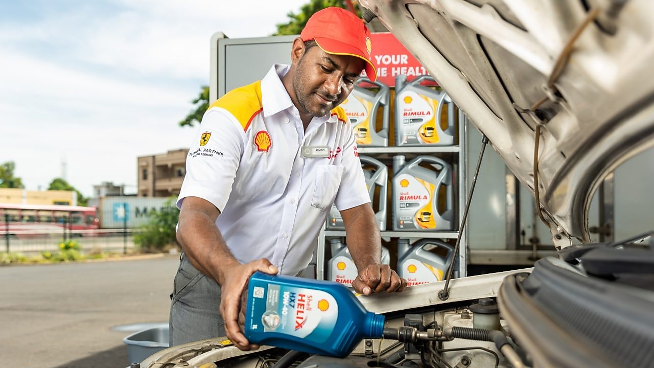 An enginner pours Shell lubricant into a car engine