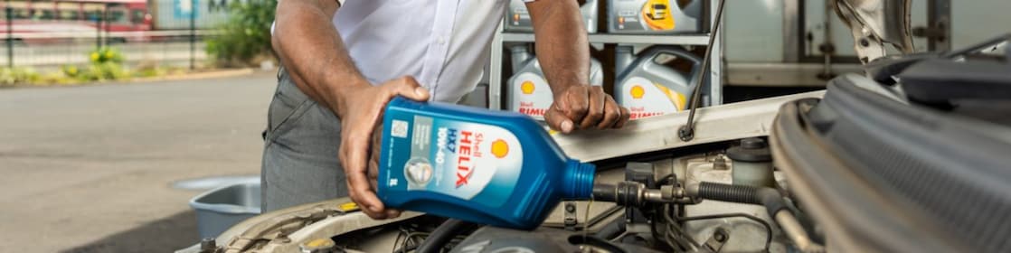 An enginner pours Shell lubricant into a car engine