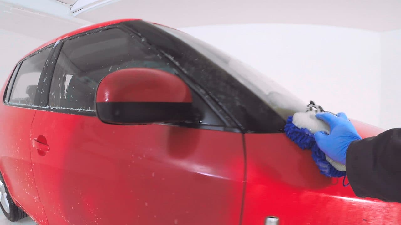 hand washing the outside of a red car