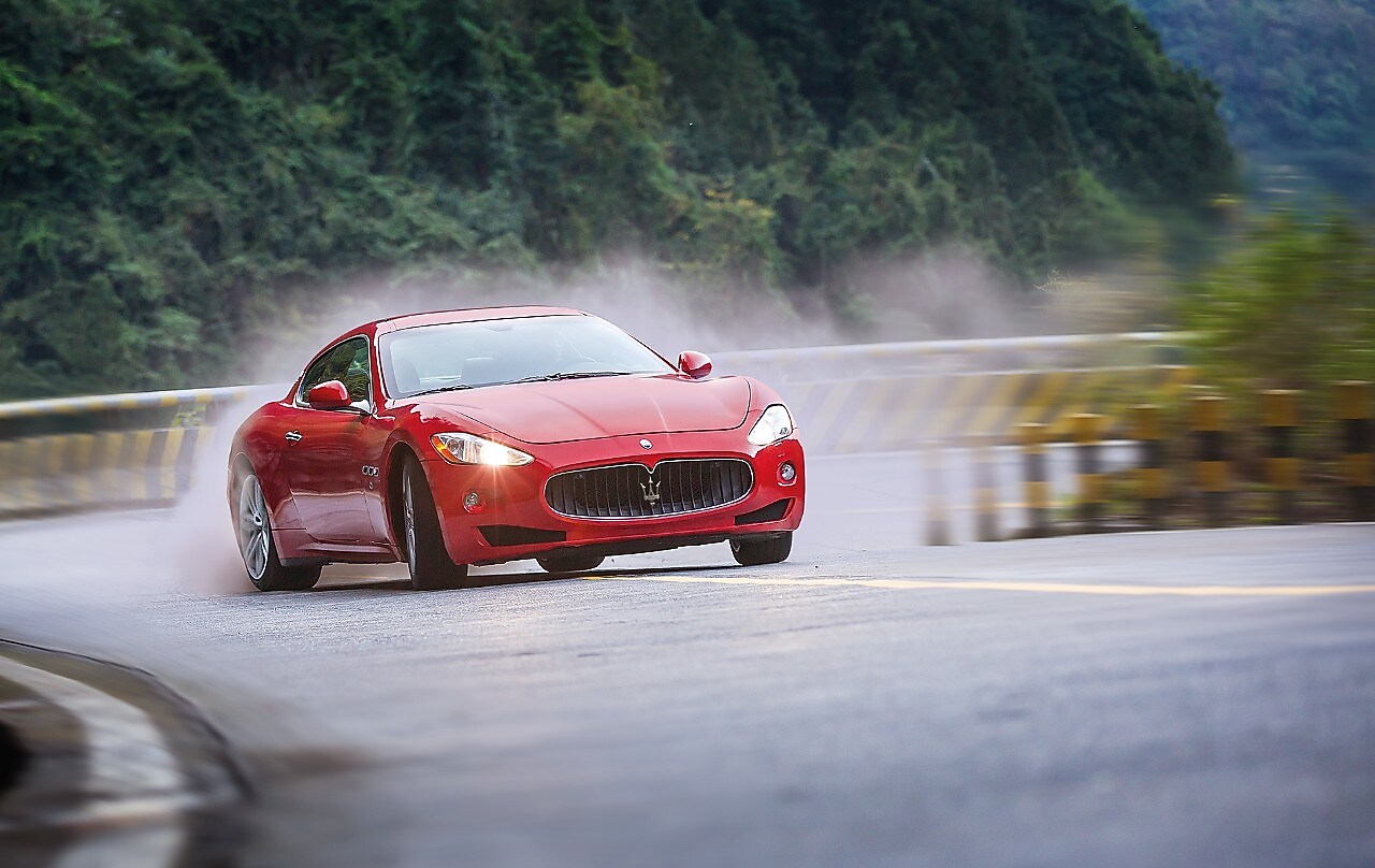 Red Maserati climbing up mountain road