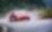 Red Maserati climbing up mountain road