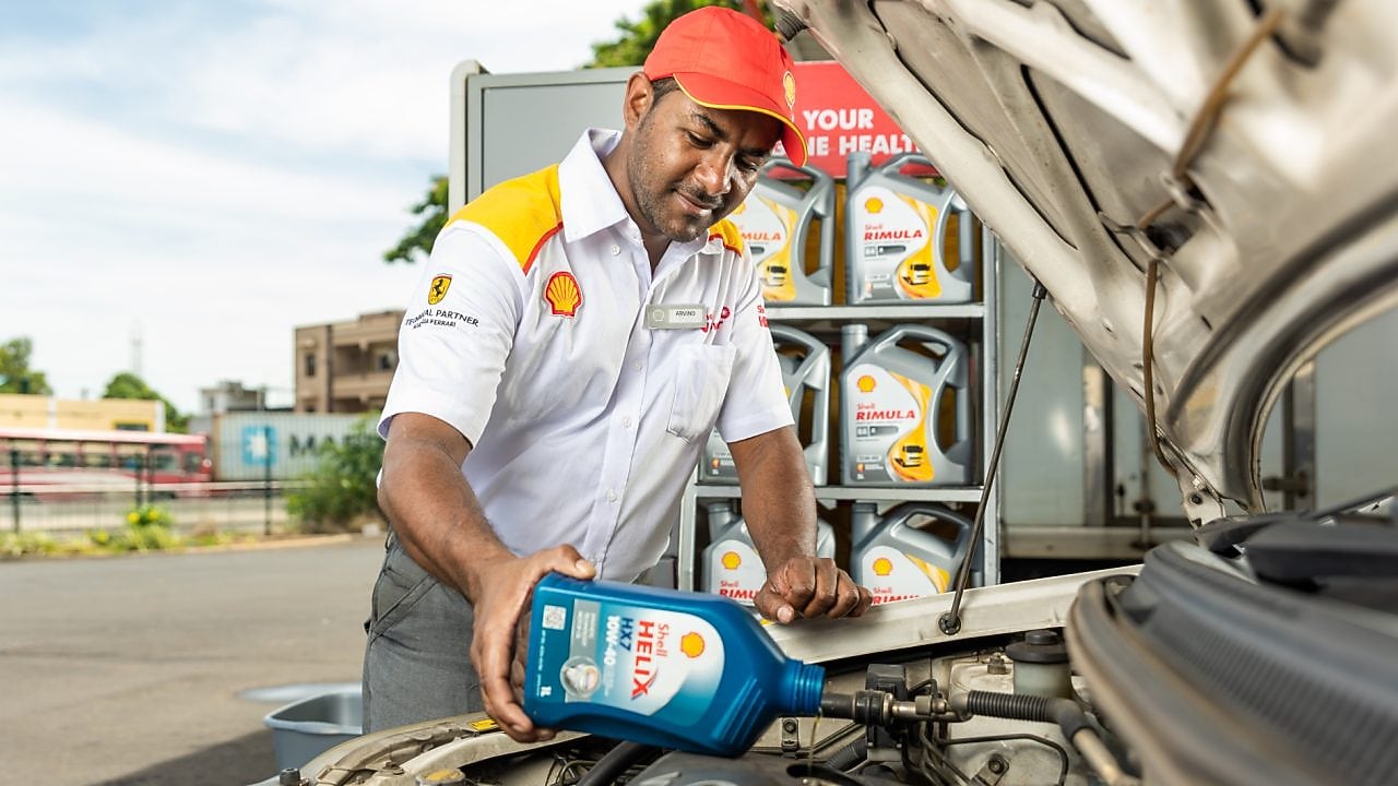 engineer pouring Shell lubricant into a car engine