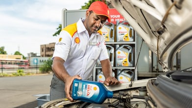 engineer pouring Shell lubricant into a car engine