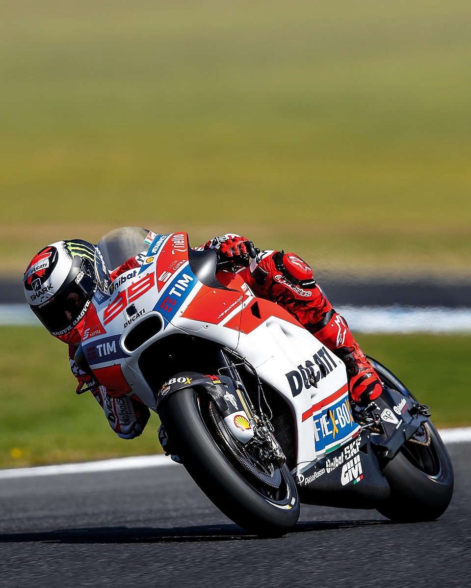 ducati superbike with rider cornering at speed on a racetrack