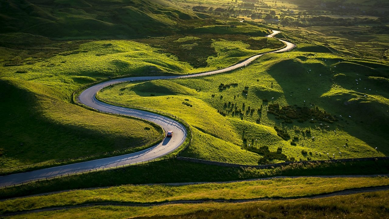 a road passing between green fields