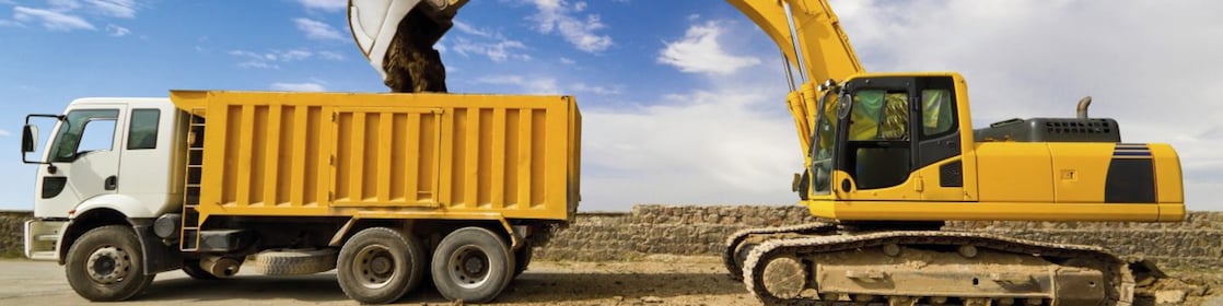 yellow excavator loading mud into a truck