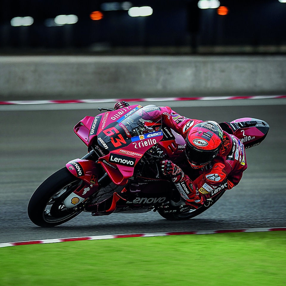 A red Ducati MotoGP bike taking a sharp turn on a race track