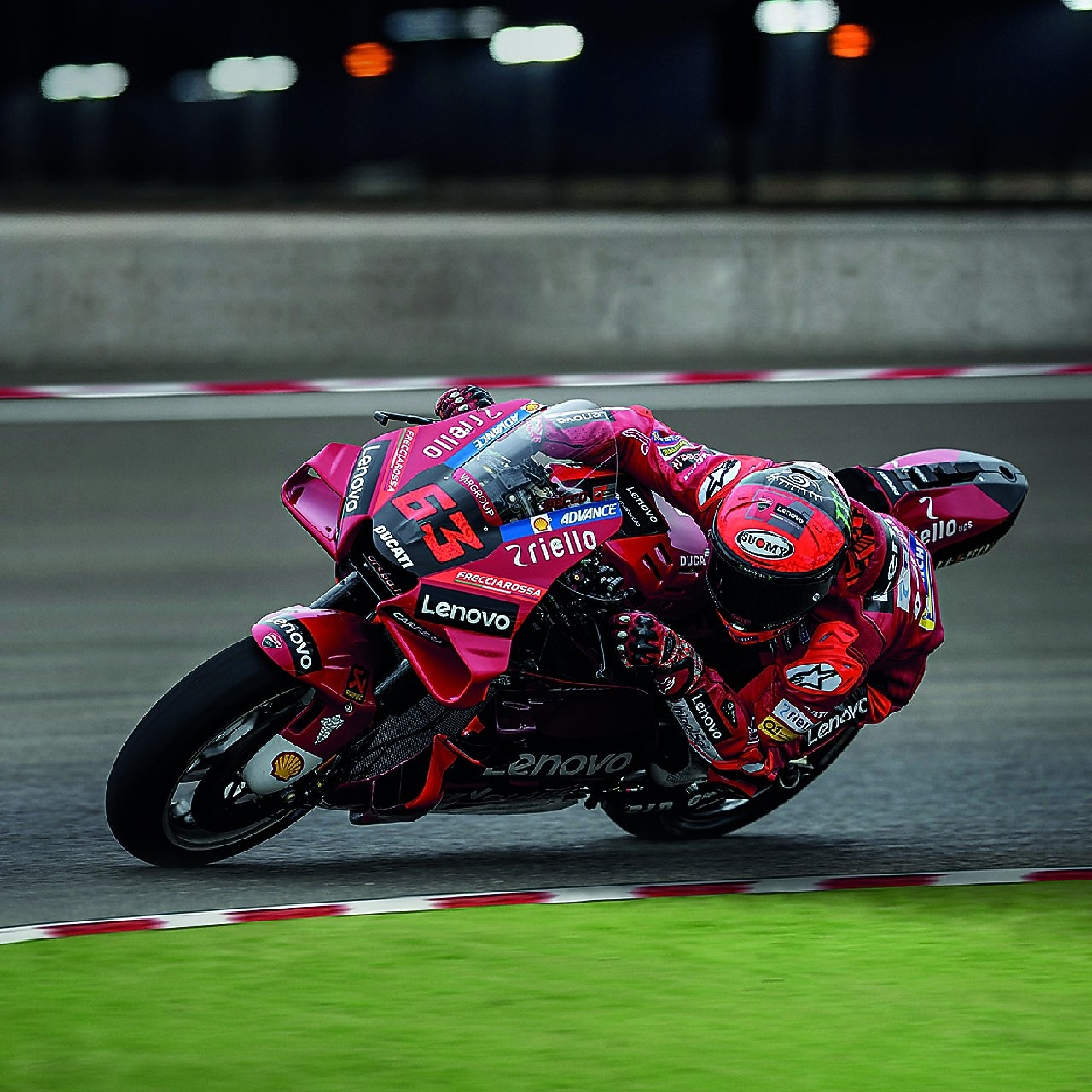 A red Ducati MotoGP bike taking a sharp turn on a race track