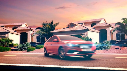 Red car parked on the street outside the house at dusk